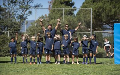 Young Stingrays players and their coaches cheering on the field