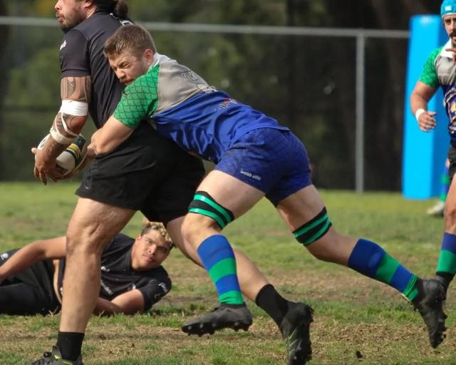 A Grunion player in the club's blue and green kit makes a tackle